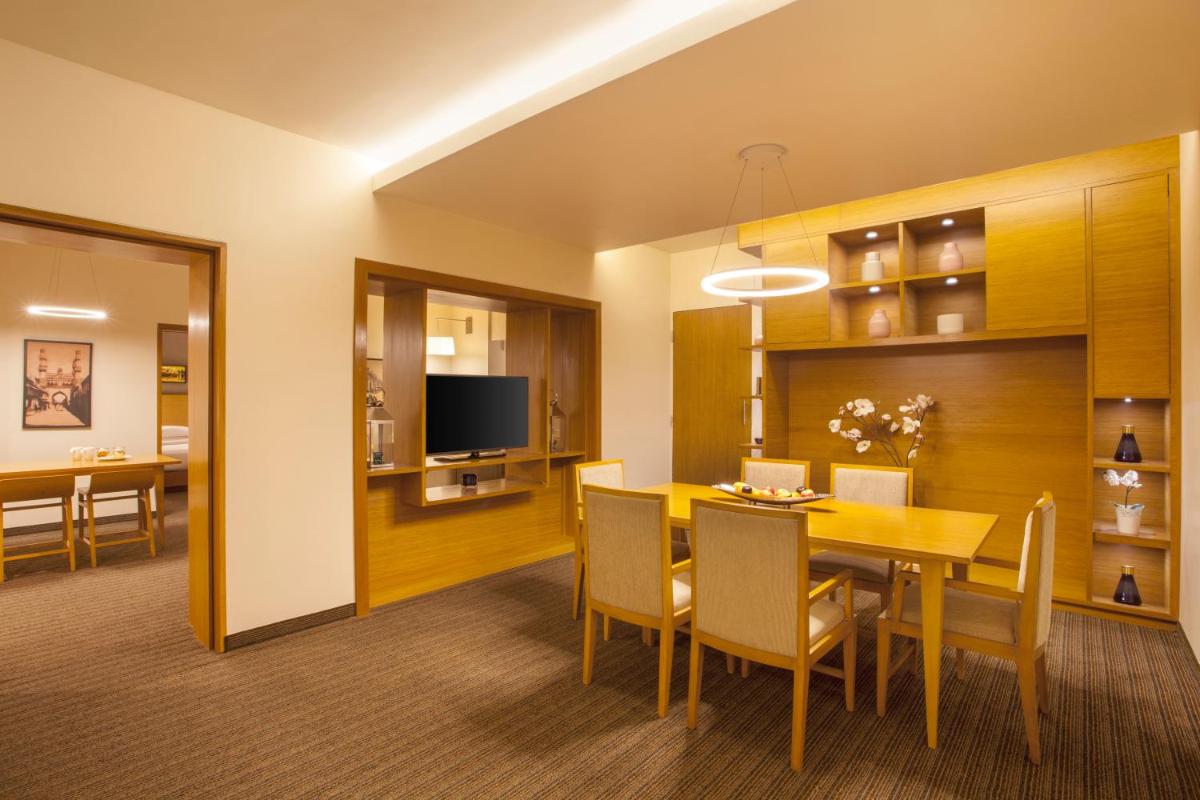 a dining room and living room with a table and chairs at Hyatt Place Hyderabad Banjara Hills in Hyderabad