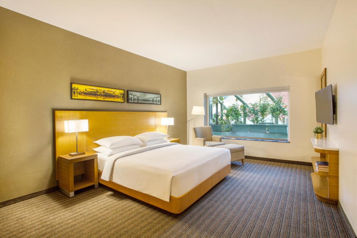 a hotel room with a bed and a television at Hyatt Place Hyderabad Banjara Hills in Hyderabad a hotel room with a bed and a television at Hyatt Place Hyderabad Banjara Hills in Hyderabad