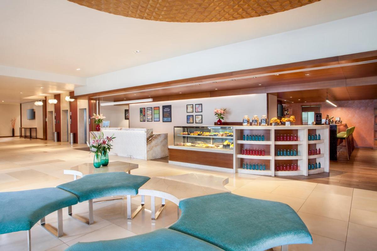 a hotel lobby with blue chairs and a counter at Hyatt Place Hyderabad Banjara Hills in Hyderabad