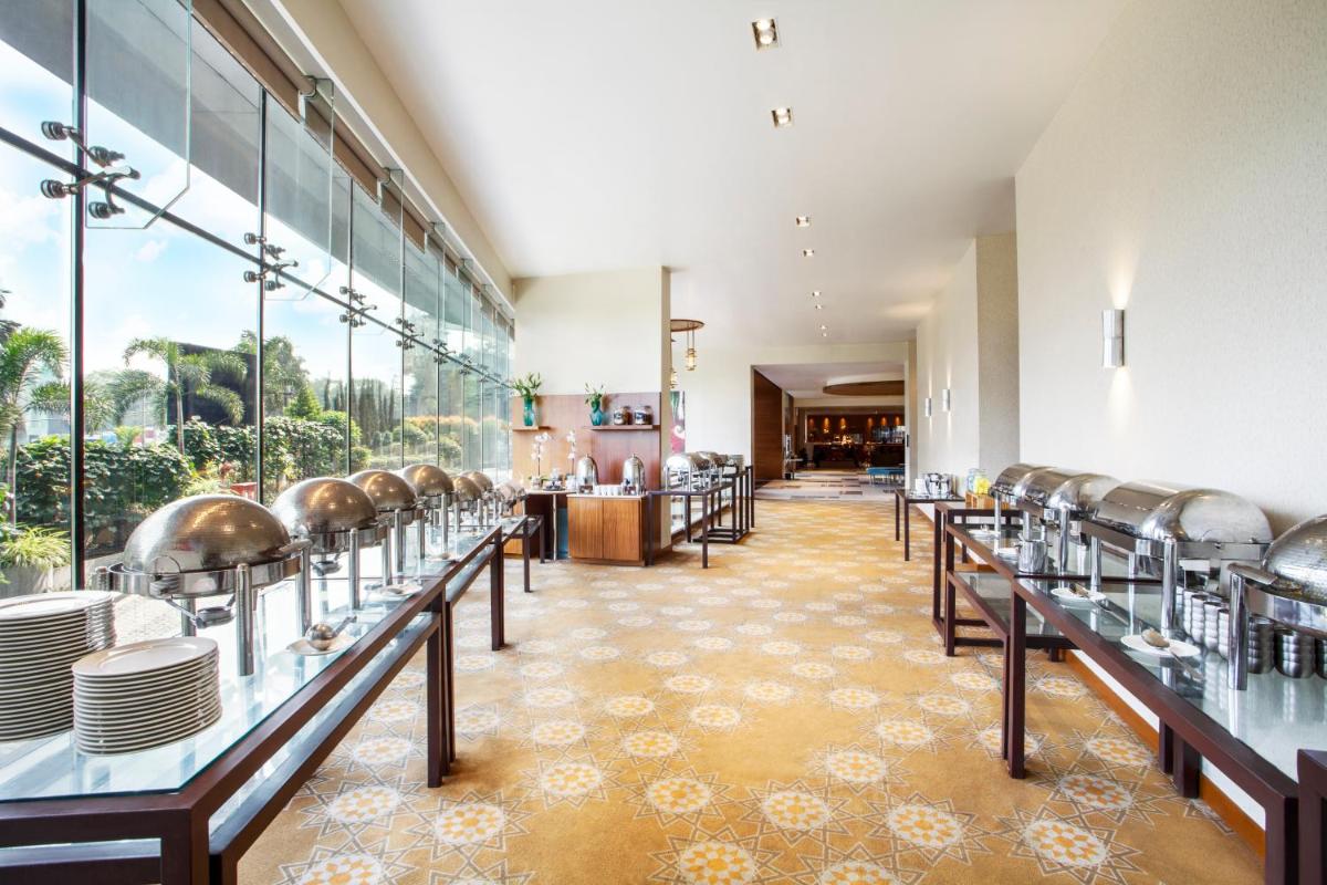 a restaurant with a row of tables and chairs at Hyatt Place Hyderabad Banjara Hills in Hyderabad