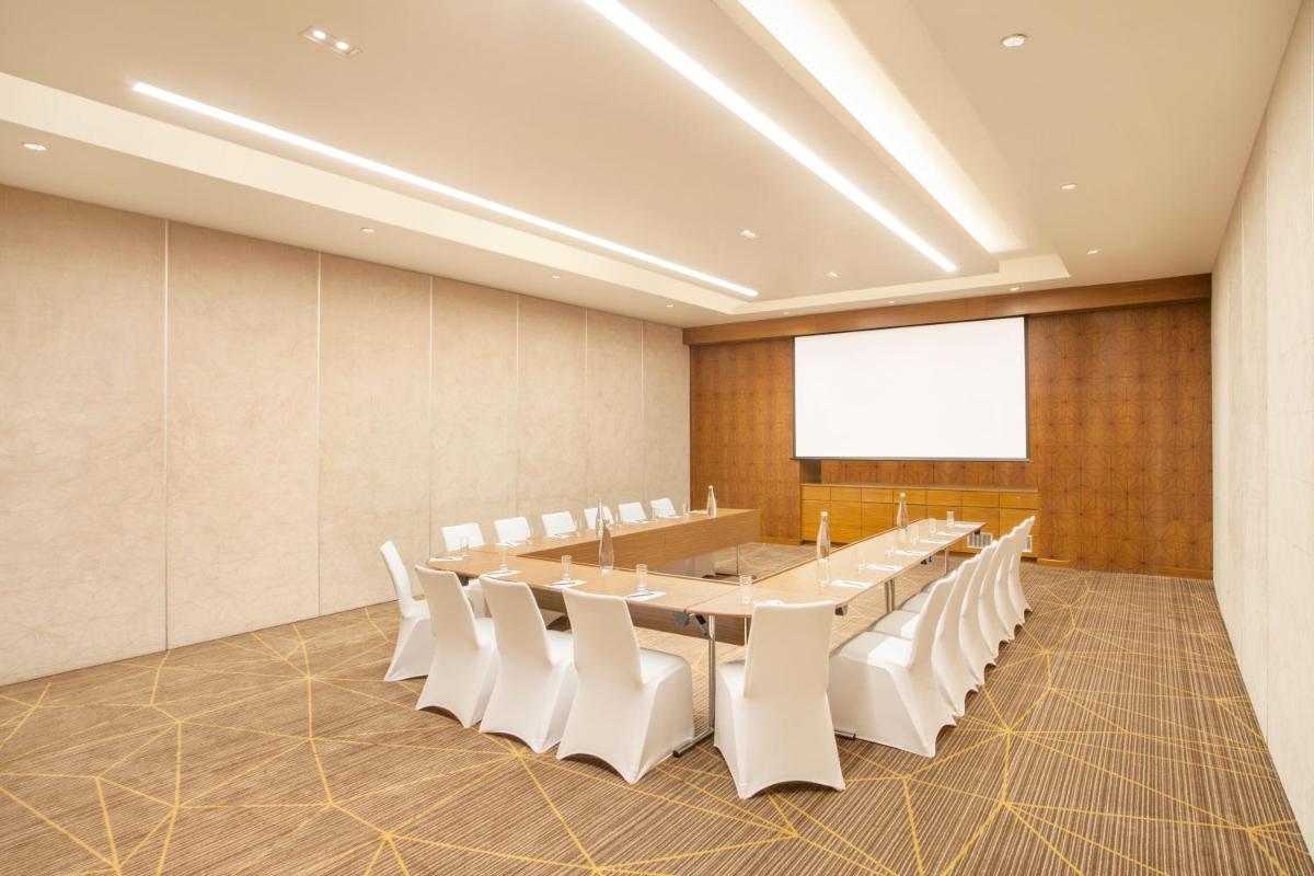 a conference room with a long table and white chairs at Hyatt Place Hyderabad Banjara Hills in Hyderabad