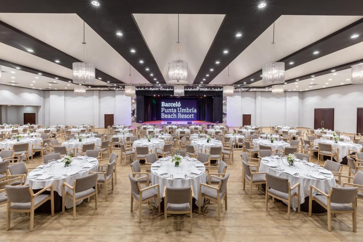 Un gran salón de banquetes con mesas y sillas blancas. en Barceló Punta Umbría Beach Resort, en Punta Umbría 100 fotos más