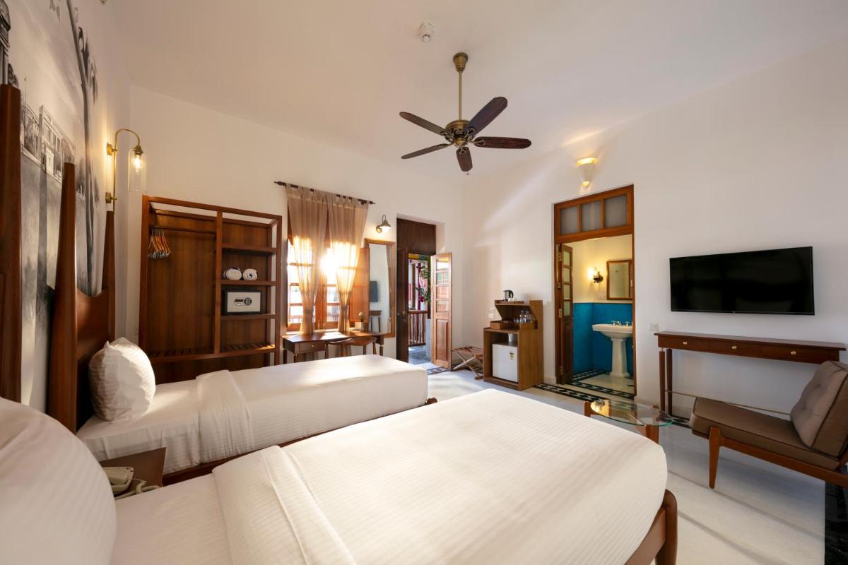 a living room with two beds and a television at Grand Hotel D'Europe in Puducherry