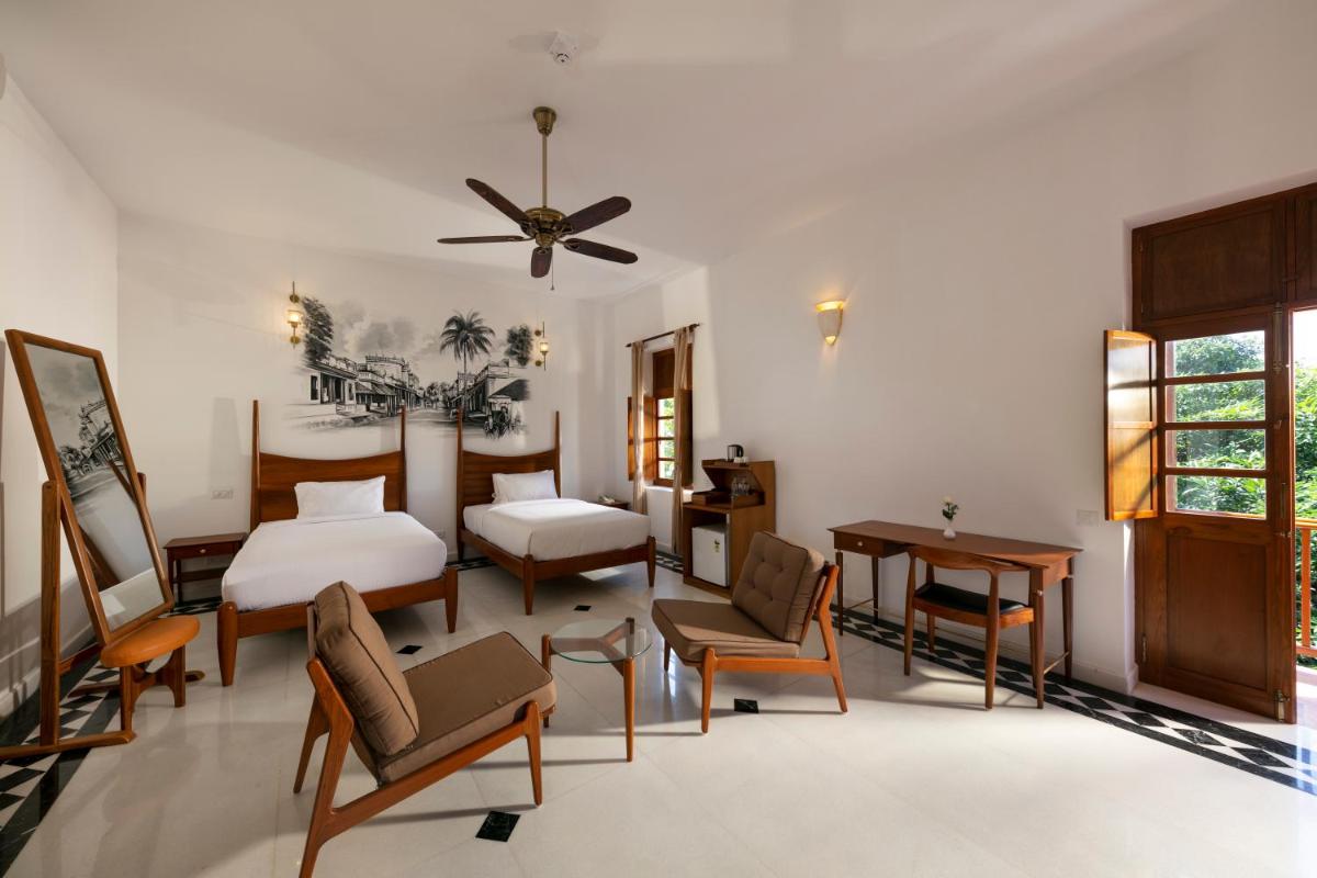 a bedroom with a bed and a table and chairs at Grand Hotel D'Europe in Puducherry