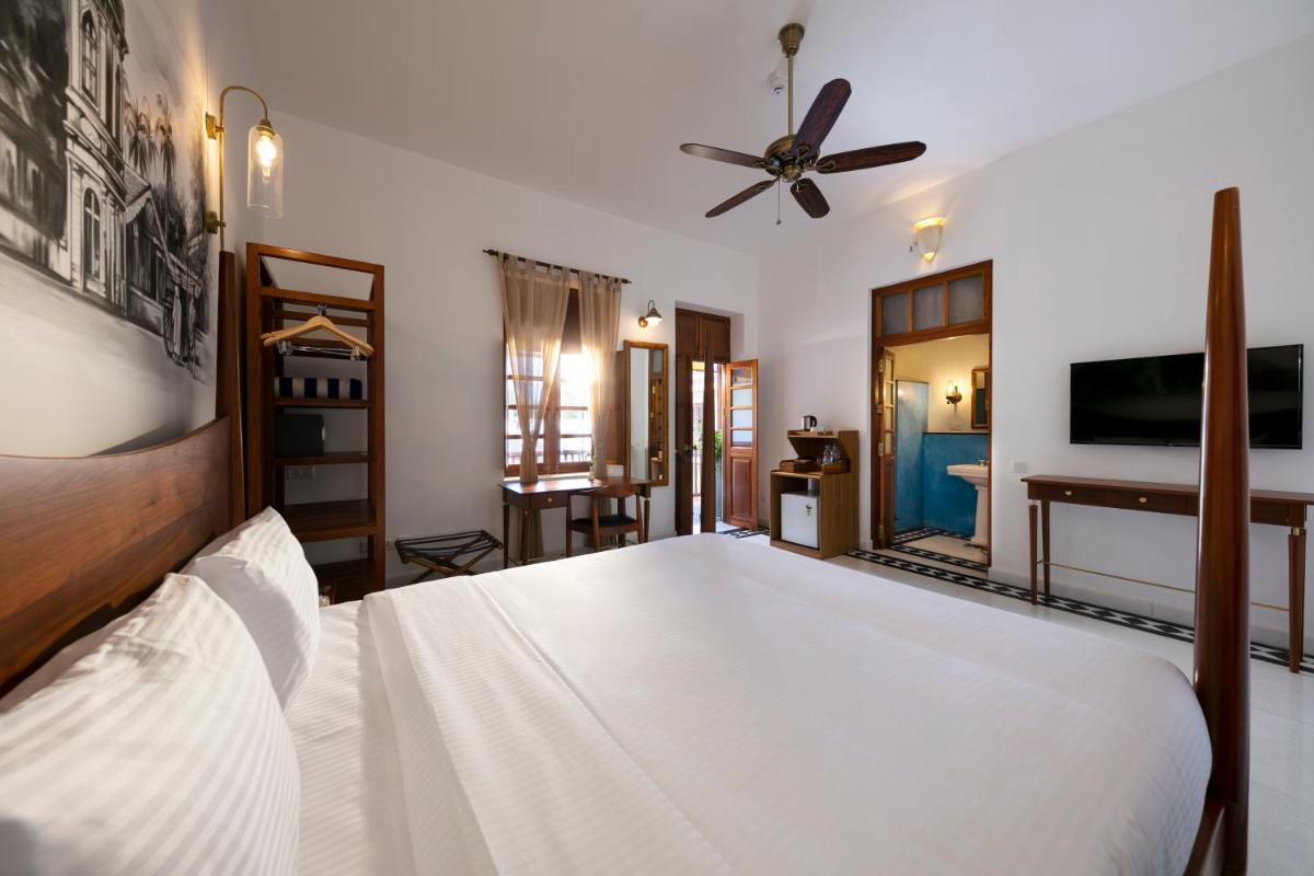 a bedroom with a white bed and a ceiling fan at Grand Hotel D'Europe in Puducherry
