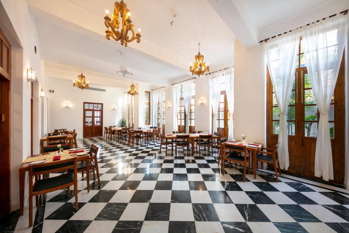 a restaurant with tables and chairs on a checkered floor at Grand Hotel D'Europe in Puducherry
