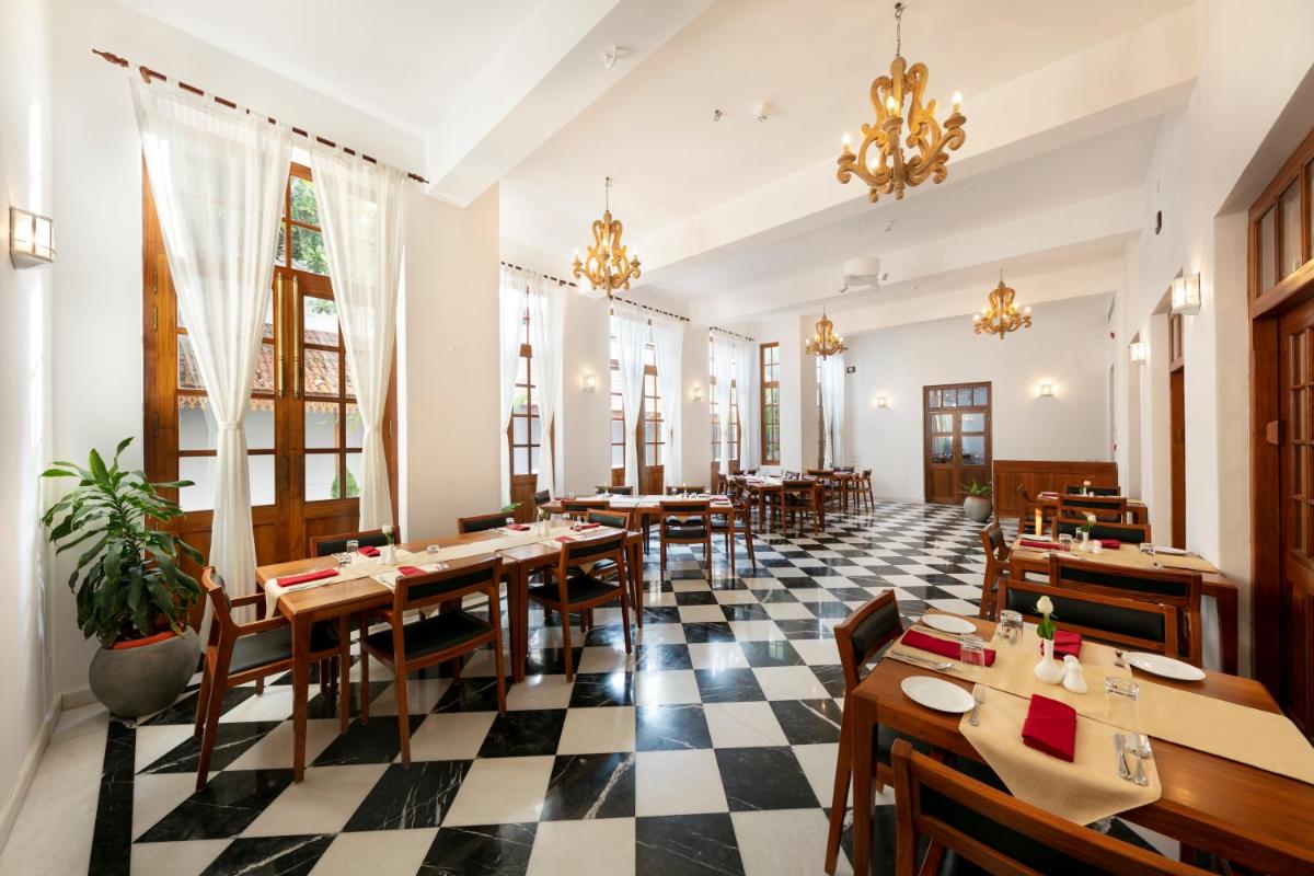 a restaurant with tables and chairs and a checkered floor at Grand Hotel D'Europe in Puducherry