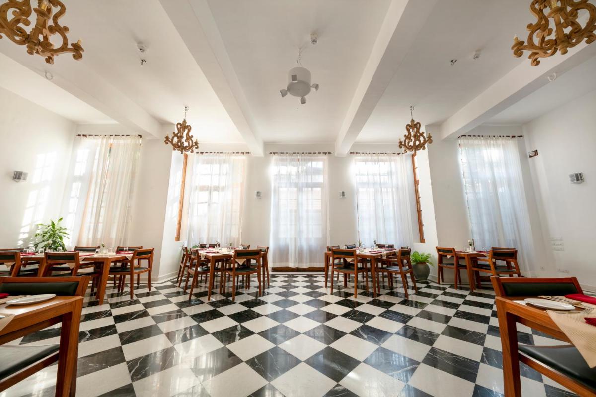 a restaurant with tables and chairs on a checkered floor at Grand Hotel D'Europe in Puducherry