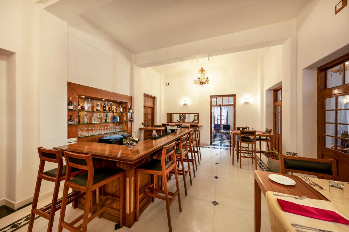 a dining room with a long bar with wooden chairs at Grand Hotel D'Europe in Puducherry
