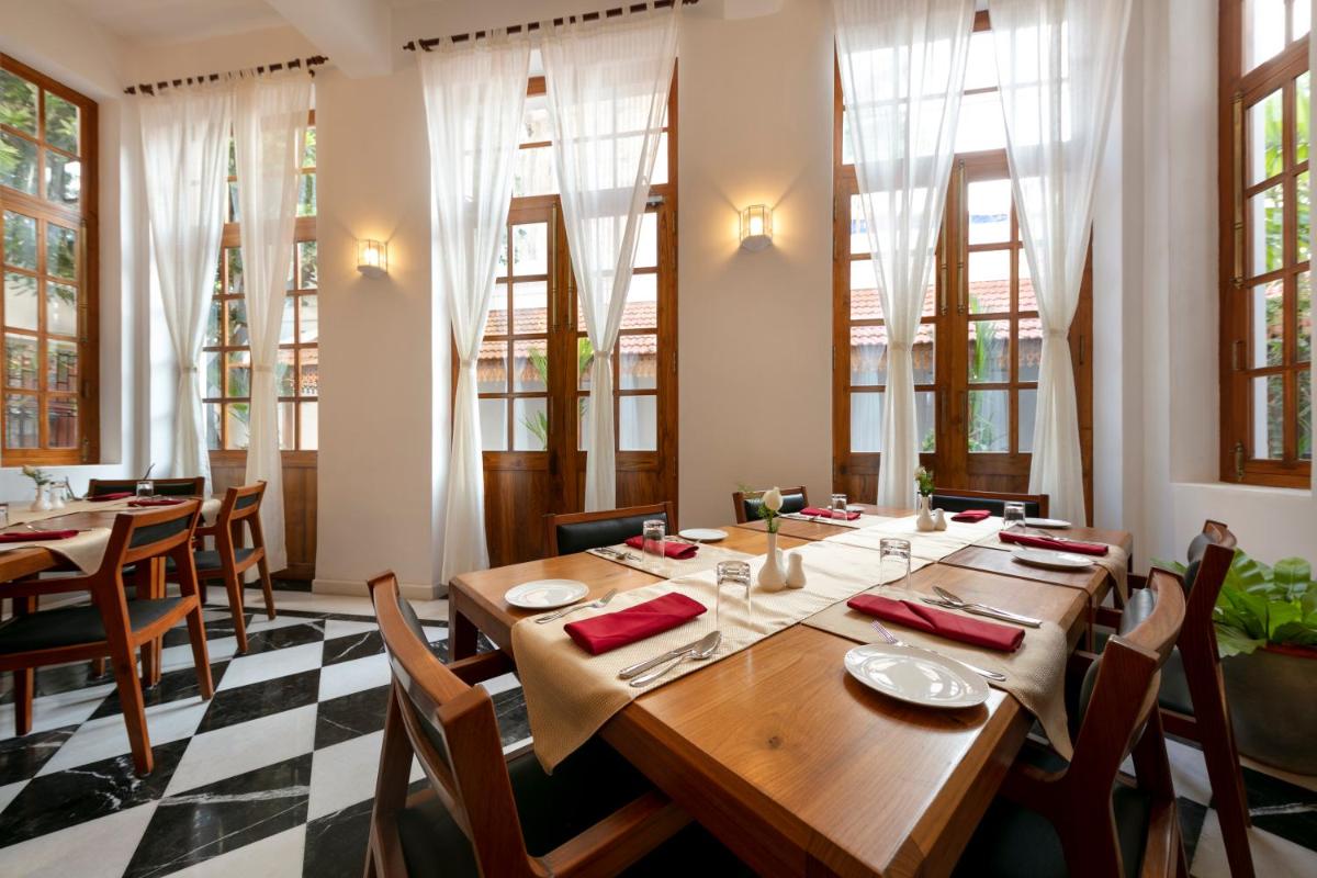 a dining room with tables and chairs and windows at Grand Hotel D'Europe in Puducherry