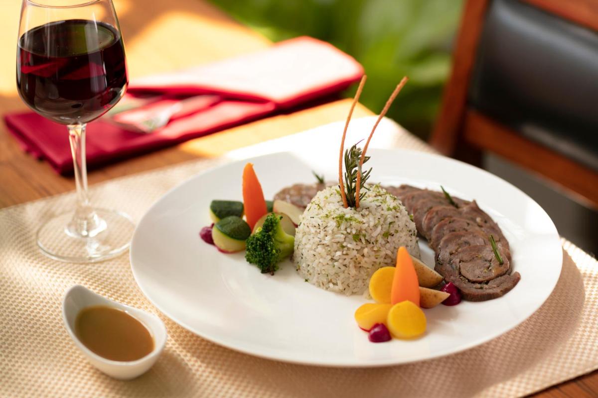 a plate of food with rice and meat and a glass of wine at Grand Hotel D'Europe in Puducherry