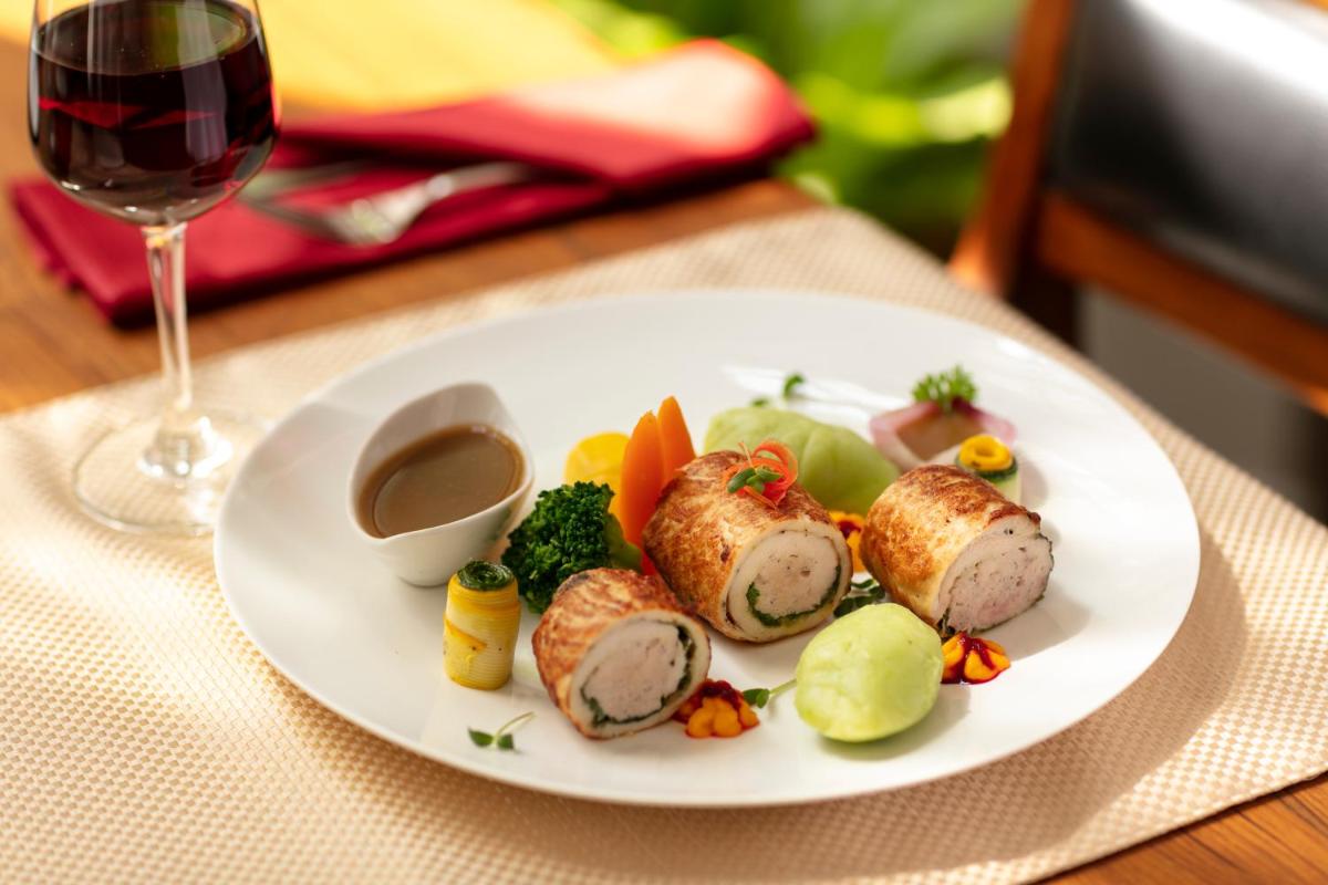 a plate of food on a table with a glass of wine at Grand Hotel D'Europe in Puducherry