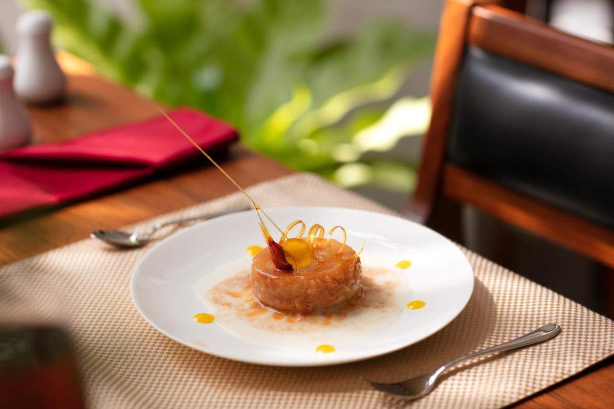 a plate with a piece of food on a table at Grand Hotel D'Europe in Puducherry