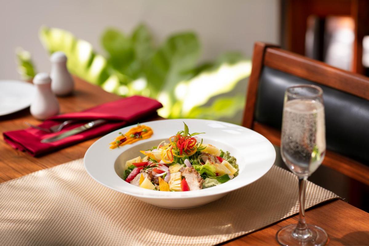 a white bowl of food on a table with a glass at Grand Hotel D'Europe in Puducherry
