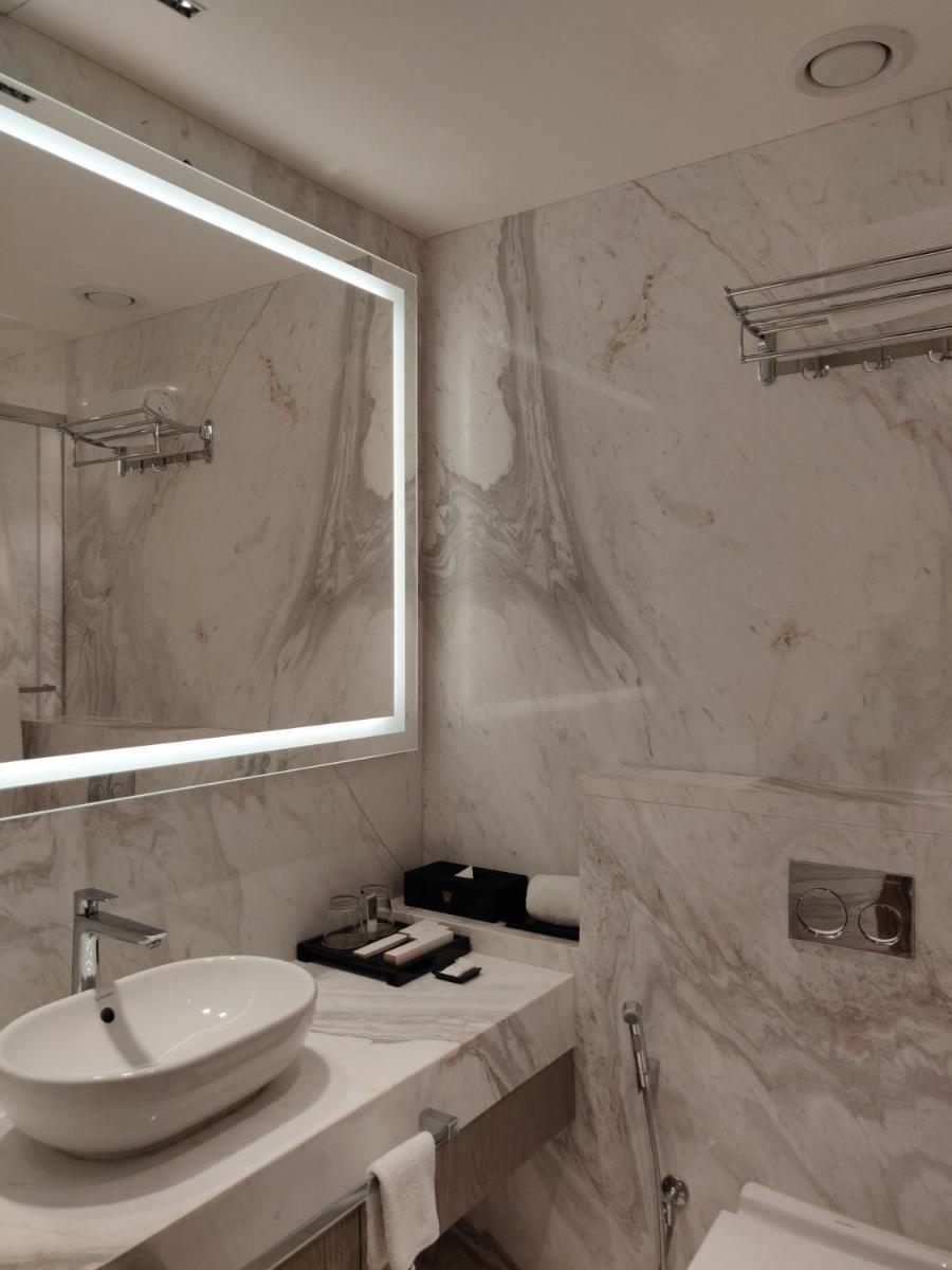 a white bathroom with a sink and a mirror at Vividus in Bengaluru a white bathroom with a sink and a mirror at Vividus in Bengaluru