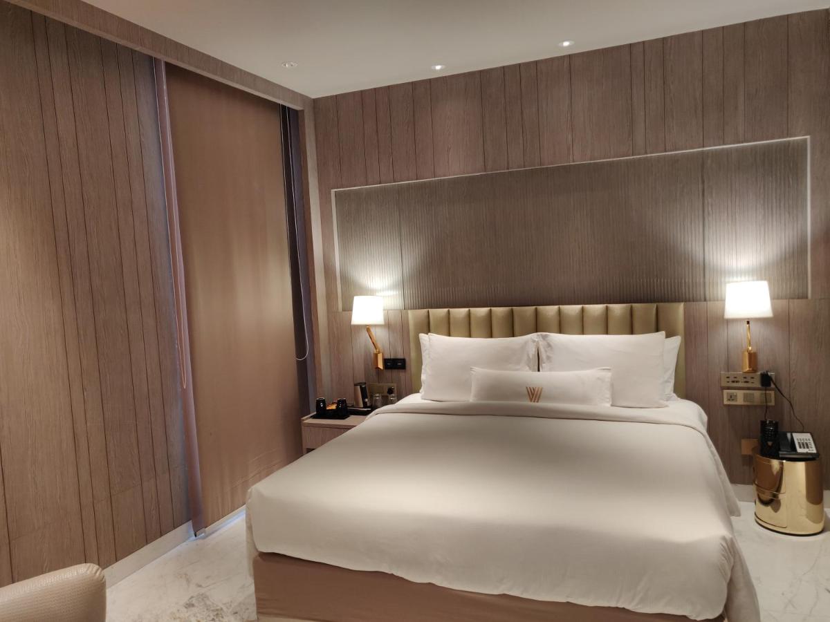 a bedroom with a large bed with white sheets at Vividus in Bengaluru a bedroom with a large bed with white sheets at Vividus in Bengaluru