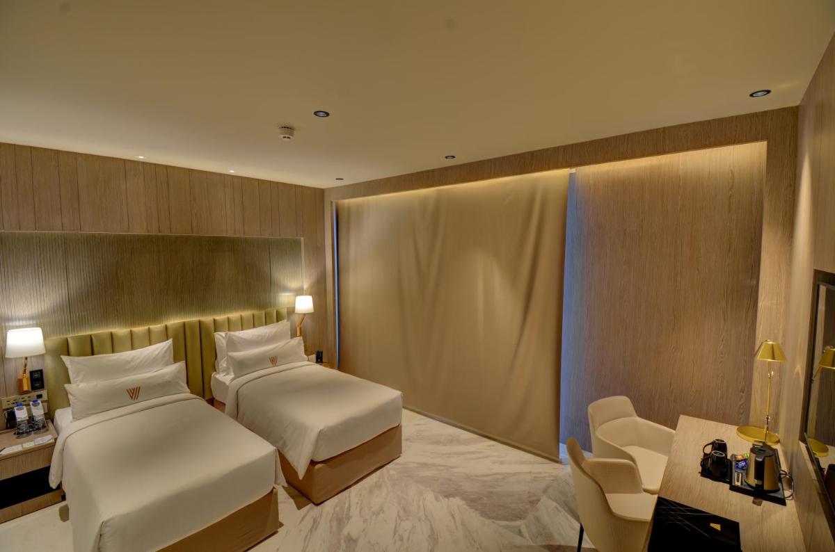 a hotel room with two beds and a chair at Vividus in Bengaluru a hotel room with two beds and a chair at Vividus in Bengaluru