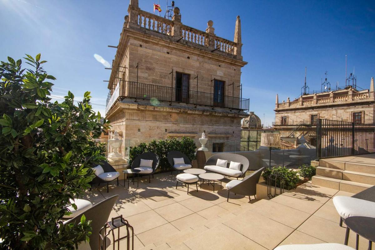 Un patio con sillas y mesas frente a un edificio. en MYR Palacio Vallier, en Valencia