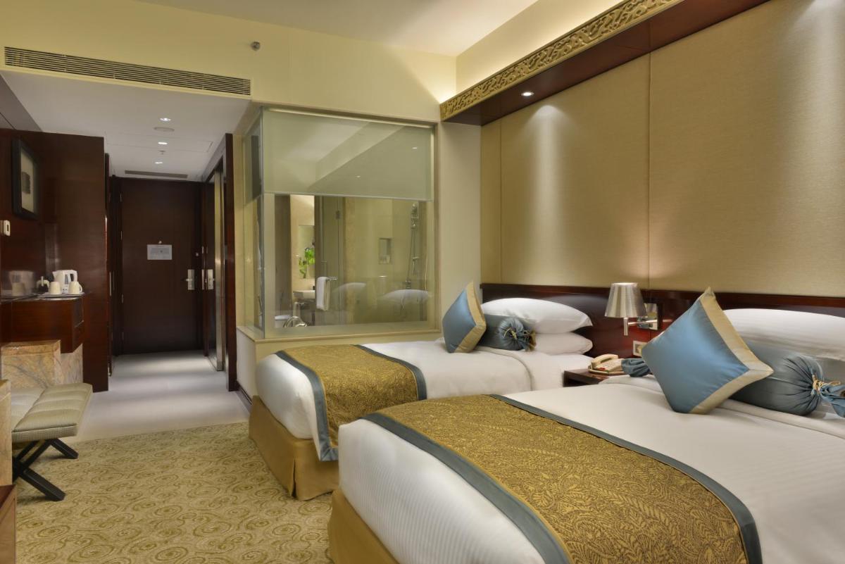 a hotel room with two beds and a bathroom at Crowne Plaza Ahmedabad City Centre by IHG in Ahmedabad