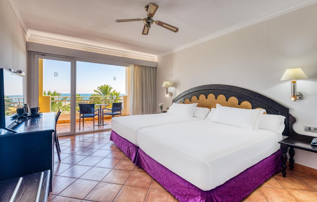 Un dormitorio con una gran cama blanca y un balcón. en Playazimbali, en Vera