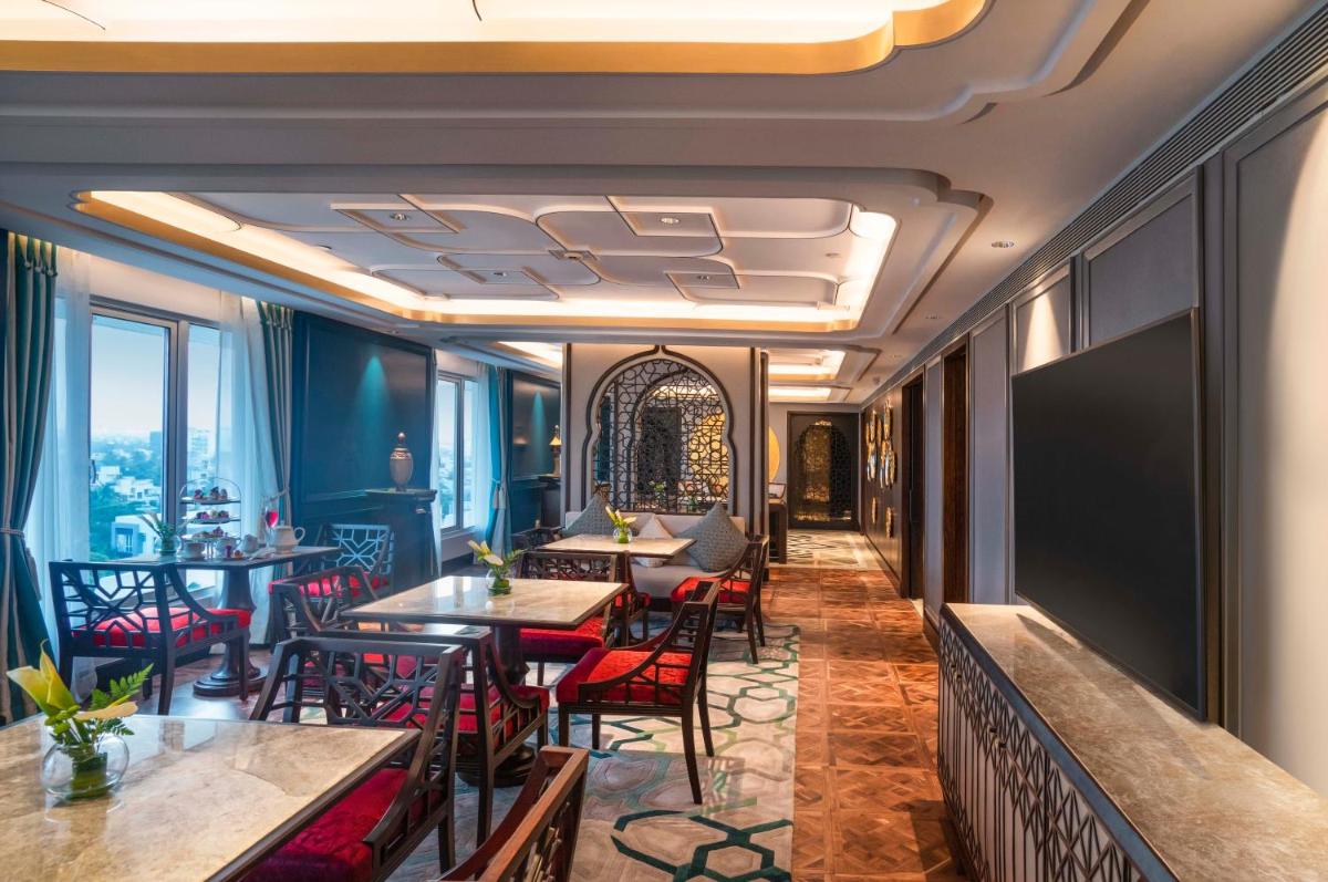 a hotel lobby with tables and chairs and windows at Taj Coromandel in Chennai