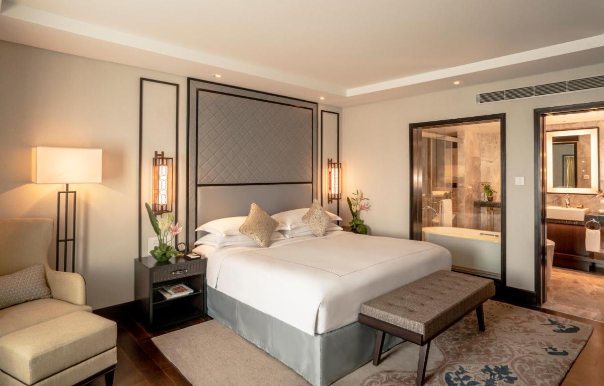 a bedroom with a large white bed and a chair at Taj Coromandel in Chennai