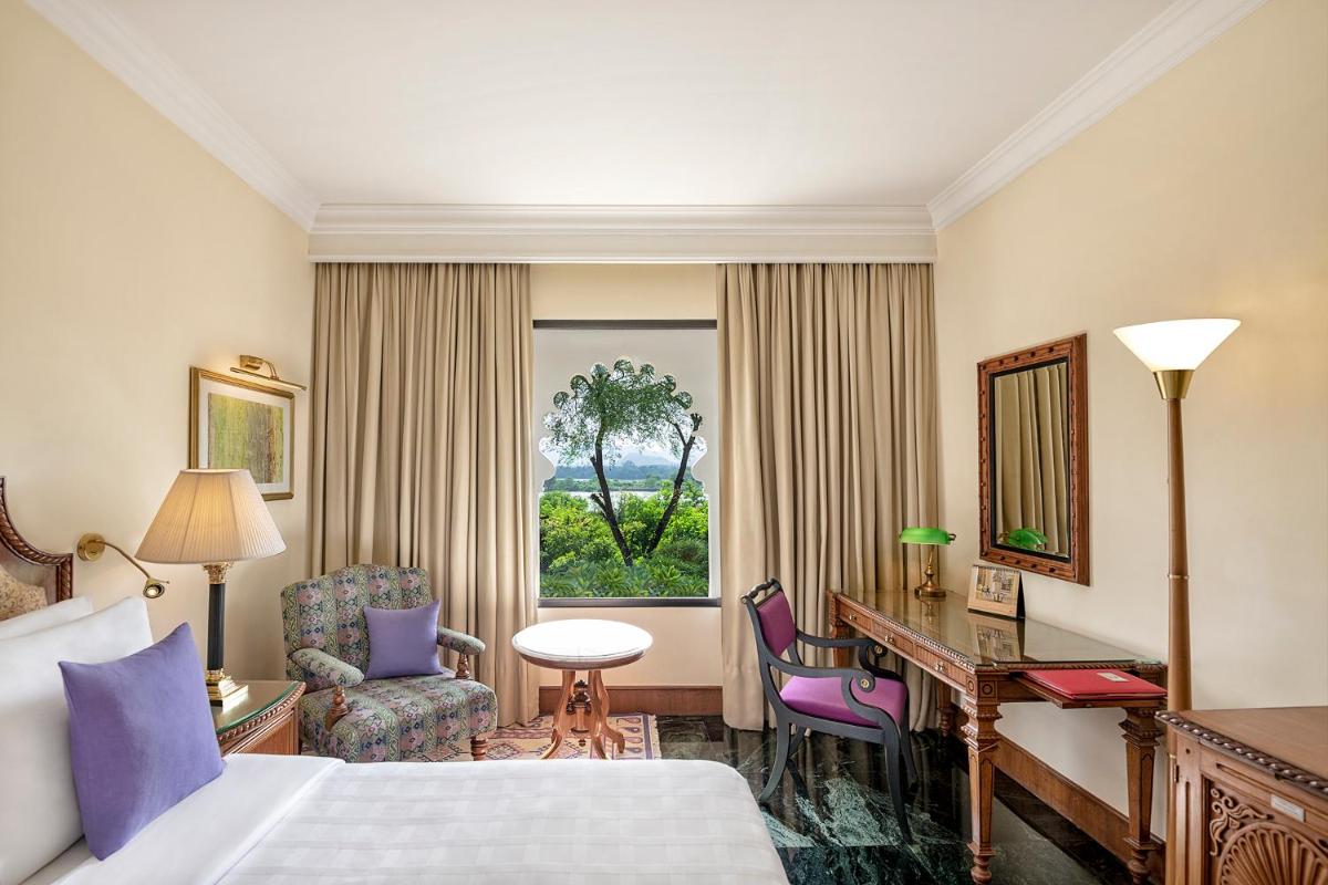 a hotel room with a bed and a desk and a window at Trident Udaipur in Udaipur