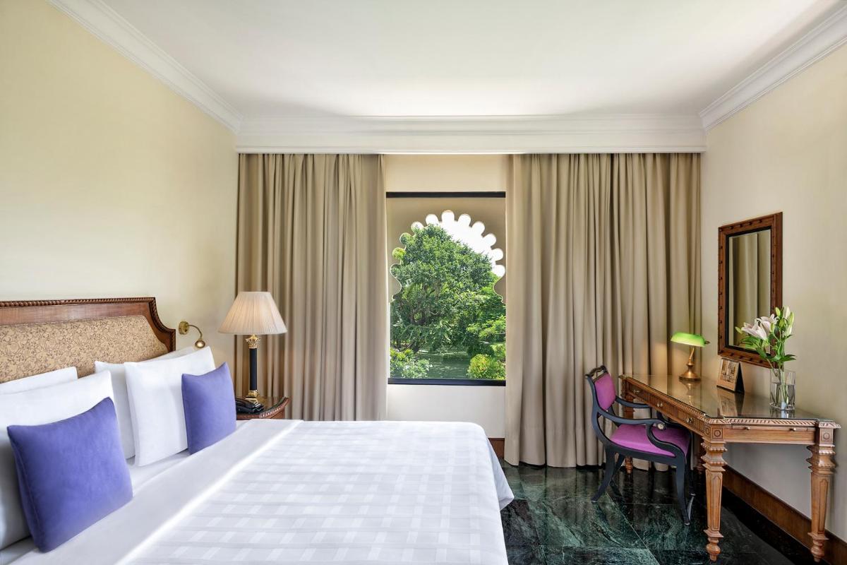 a hotel room with a bed and a desk and a window at Trident Udaipur in Udaipur