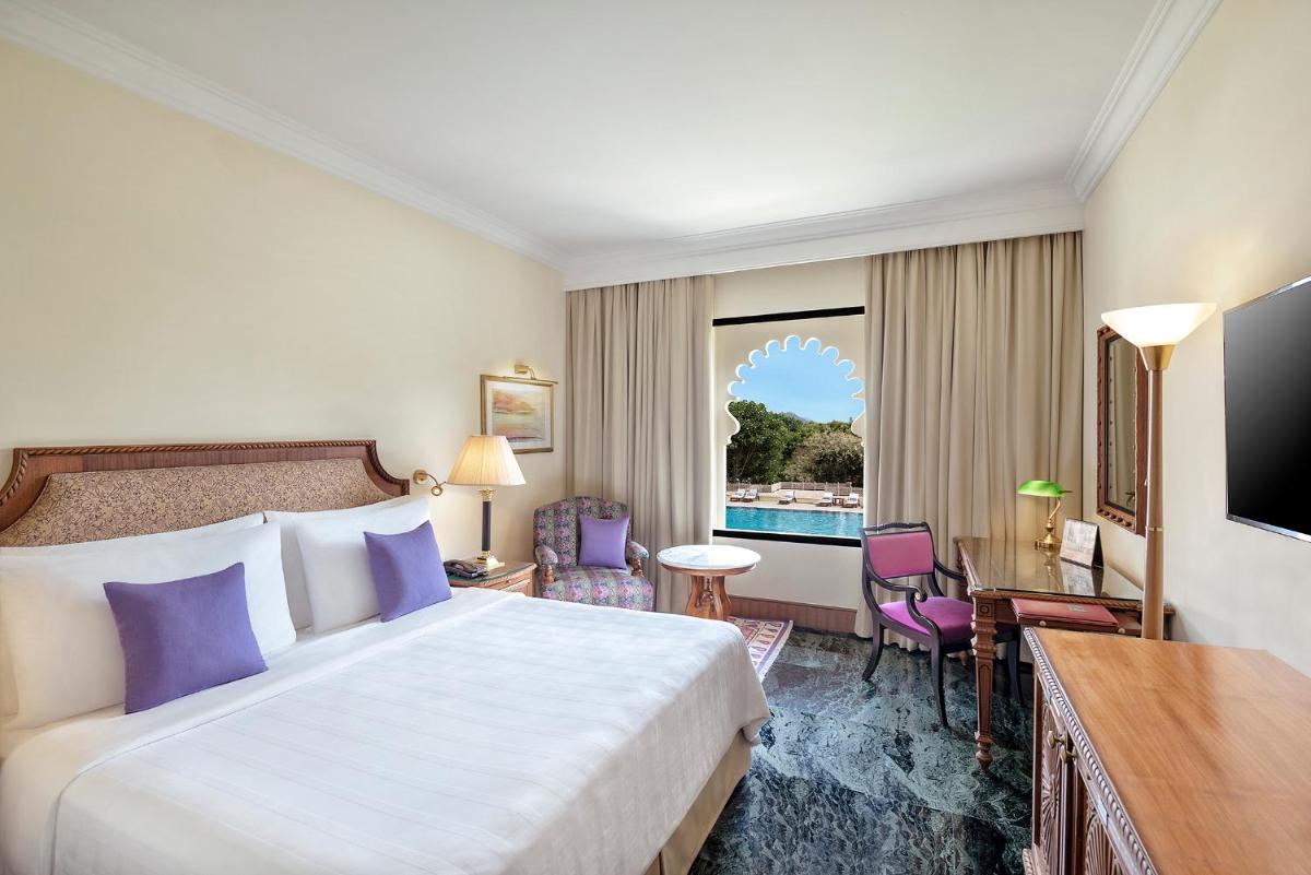 a hotel room with a bed and a large window at Trident Udaipur in Udaipur