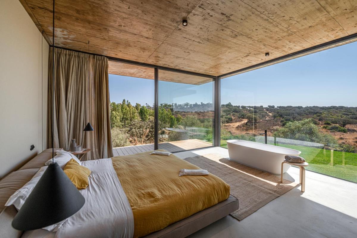 um quarto com uma cama grande e uma banheira em Herdade da Malhadinha Nova - Relais & Châteaux em Albernoa