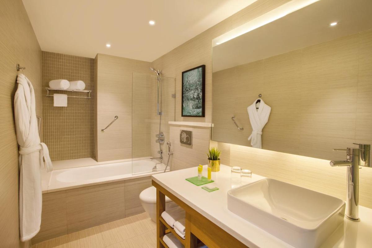 a bathroom with a sink and a tub and a toilet at Hyatt Place Hyderabad Banjara Hills in Hyderabad