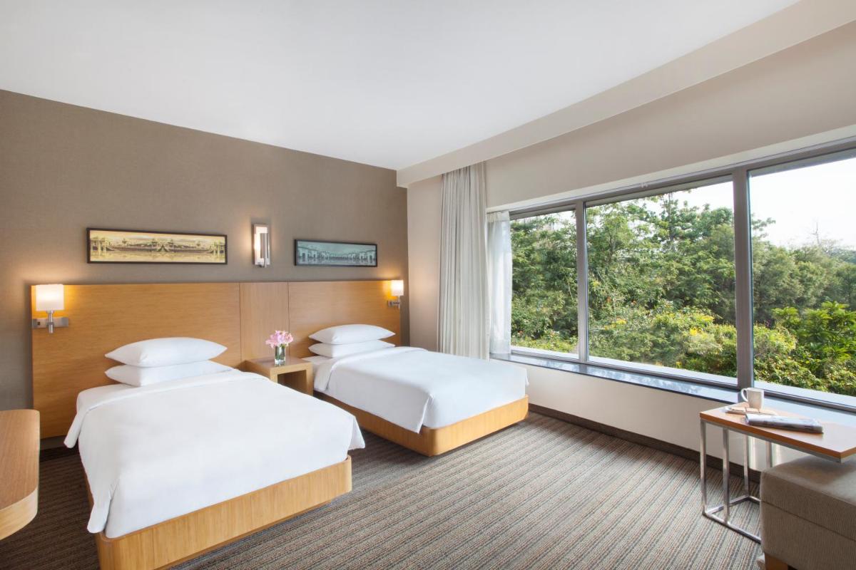 two beds in a hotel room with a large window at Hyatt Place Hyderabad Banjara Hills in Hyderabad