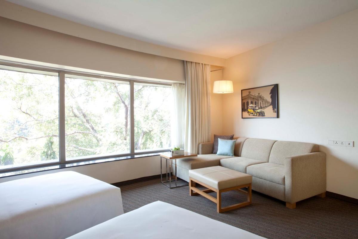 a hotel room with a couch and a window at Hyatt Place Hyderabad Banjara Hills in Hyderabad a hotel room with a couch and a window at Hyatt Place Hyderabad Banjara Hills in Hyderabad