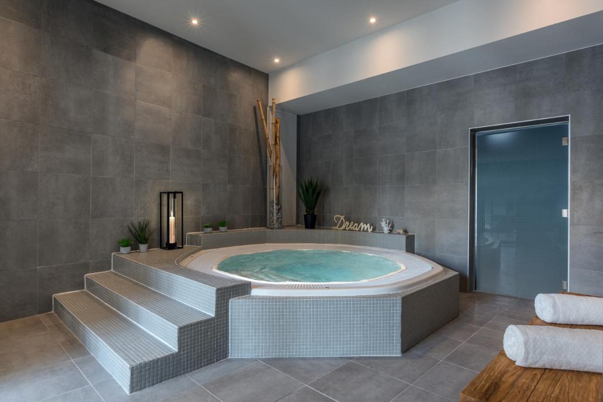La salle de bains est pourvue d'un jacuzzi et d'escaliers. dans l'établissement Hotel du Roi & Spa by SOWELL COLLECTION, à Carcassonne
