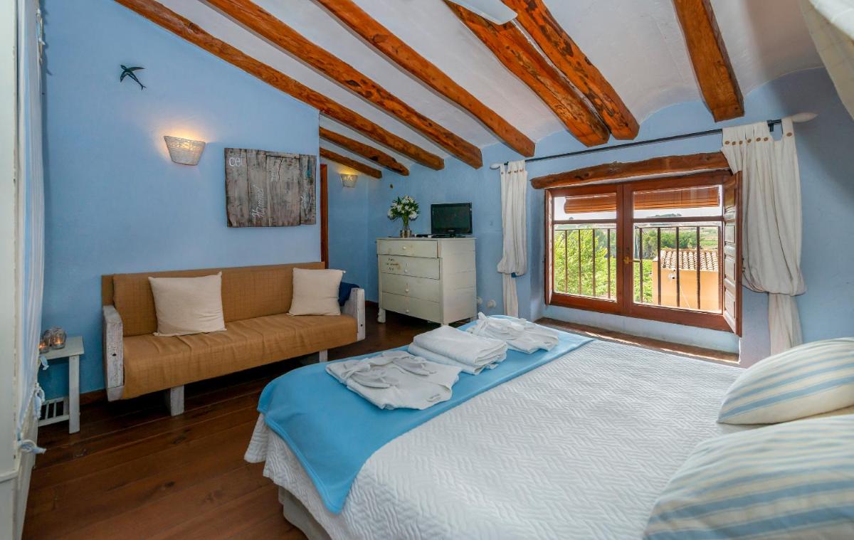 Un dormitorio con una cama y un sofá y una ventana. en Les Vinyes Alojamiento Rural Boutique & SPA, en Vilardida Un dormitorio con una cama y un sofá y una ventana. en Les Vinyes Alojamiento Rural Boutique & SPA, en Vilardida