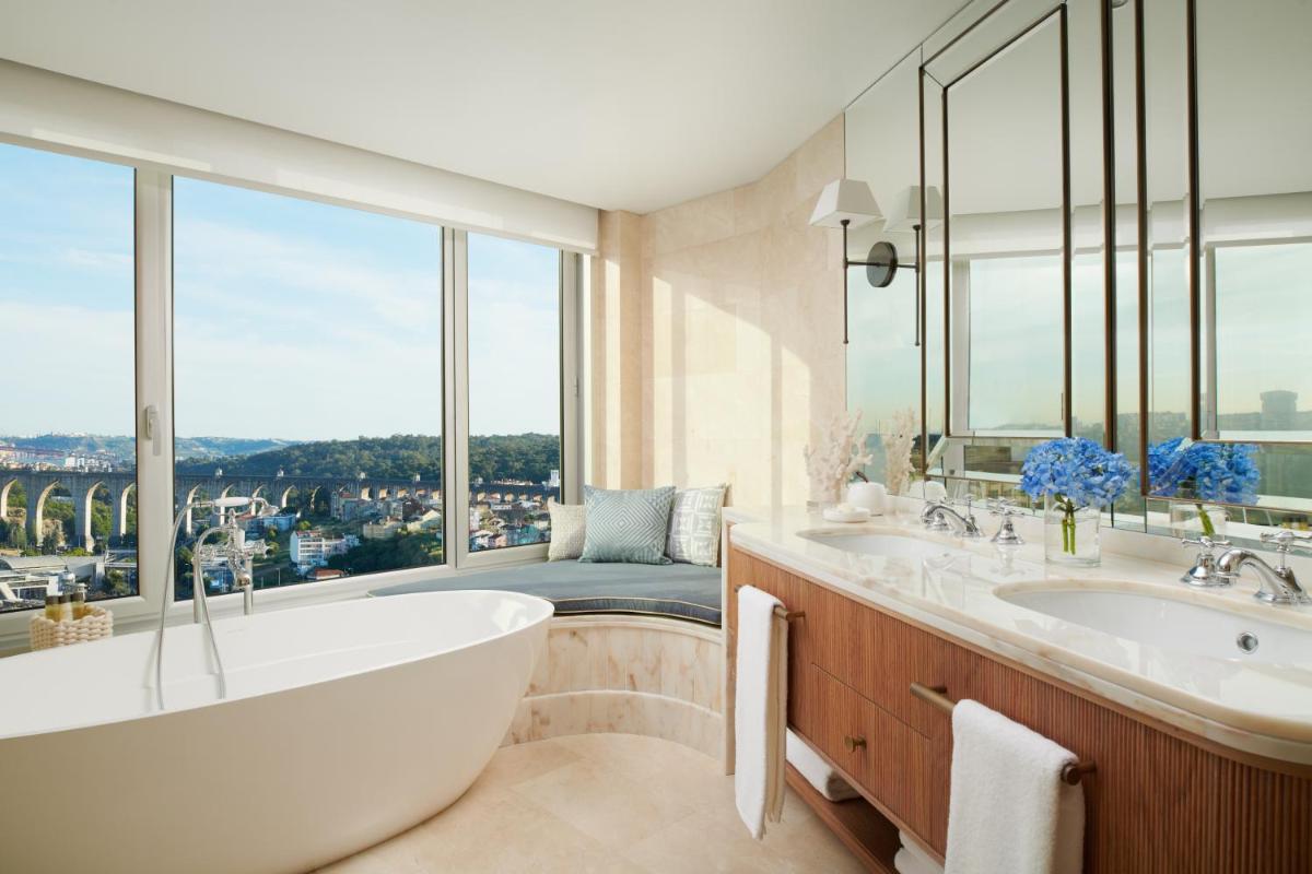 um banheiro com banheira e uma janela grande em Corinthia Lisbon em Lisboa