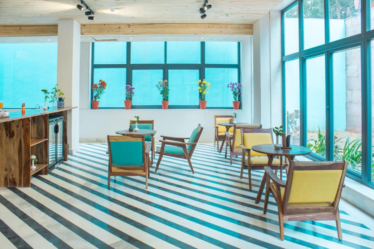 a living room with tables and chairs and windows at Brij Nest, Jaipur - An All Suite Boutique Hotel in Jaipur