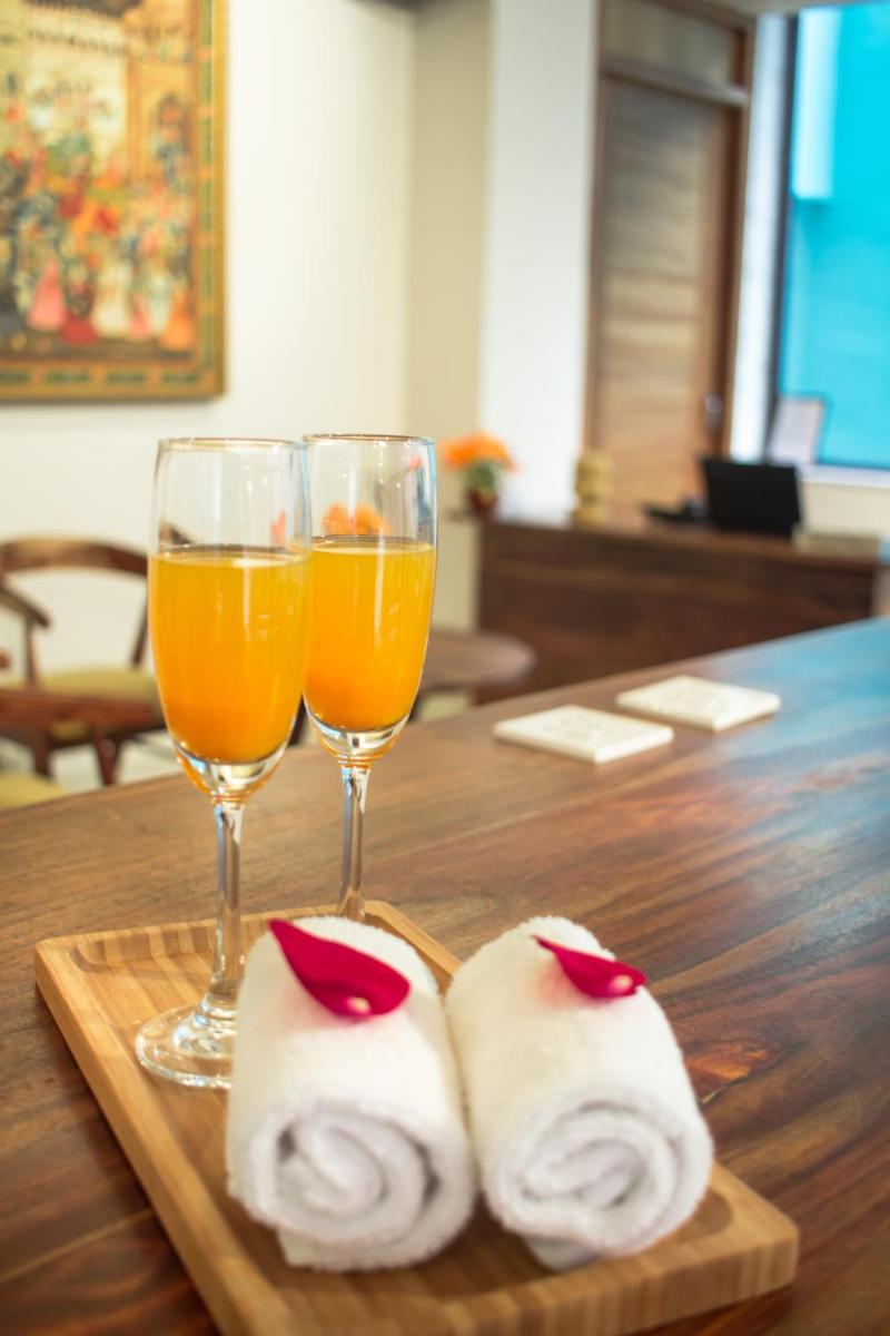 two glasses of orange juice and rolls on a wooden table at Brij Nest, Jaipur - An All Suite Boutique Hotel in Jaipur