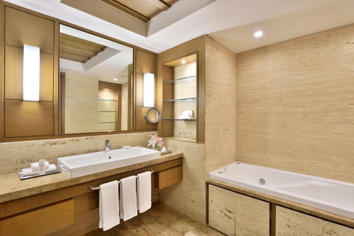 a bathroom with a sink and a tub and a mirror at Radisson Blu Hotel, Indore in Indore