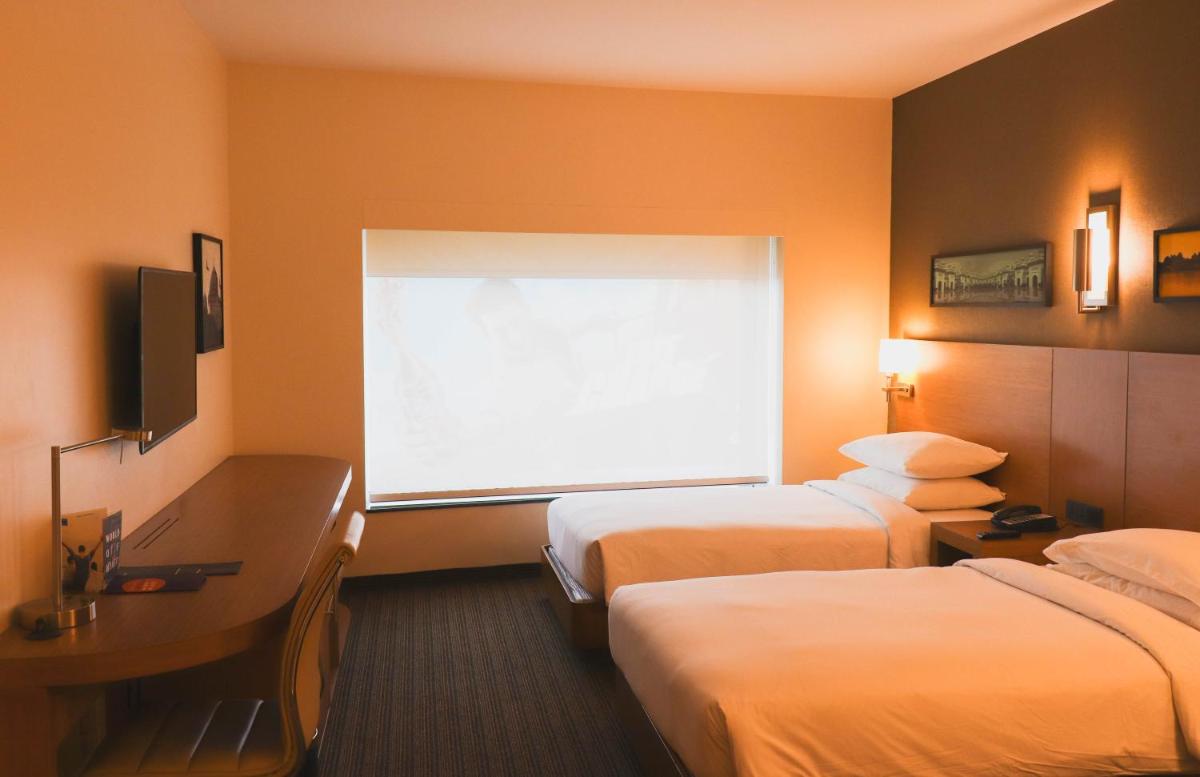 a hotel room with two beds and a window at Hyatt Place Hyderabad Banjara Hills in Hyderabad