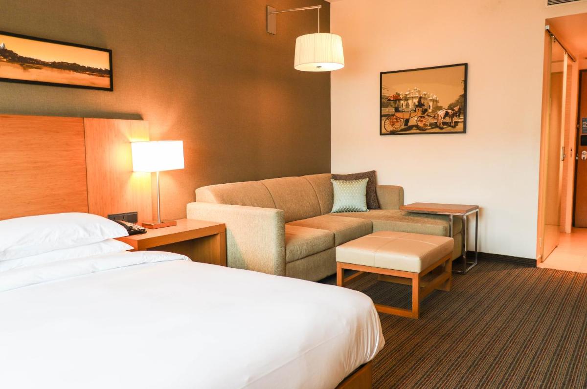 a hotel room with a bed and a couch at Hyatt Place Hyderabad Banjara Hills in Hyderabad