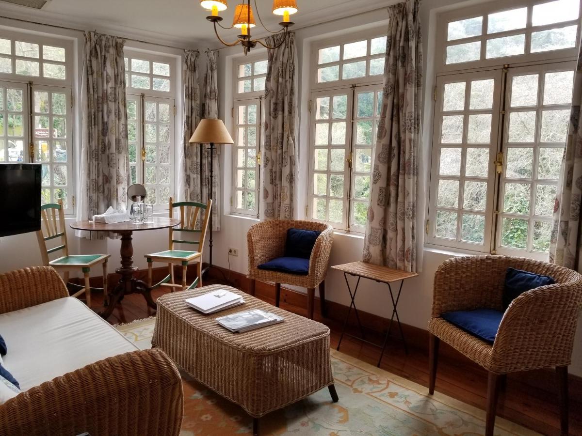 uma sala de estar com um sofá, cadeiras e janelas em Lawrences Hotel em Sintra