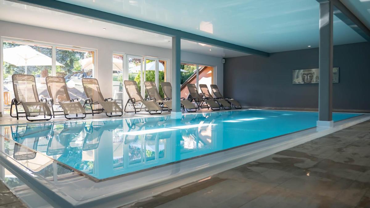 une piscine avec un tas de chaises autour dans l'établissement Hotel Spa et Restaurant Au Chasseur, à Birkenwald