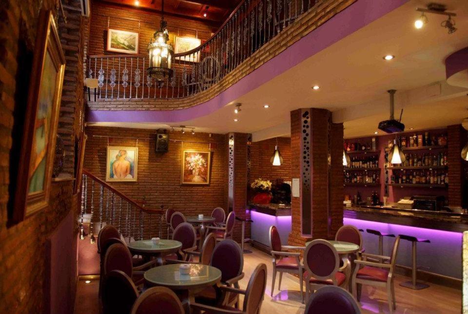 Un restaurante con mesas y sillas y un bar. en Hotel Palacio de Oñate, en Guadix