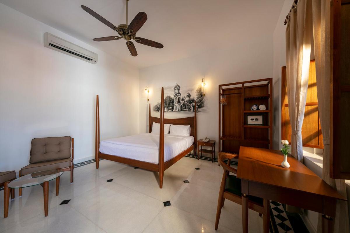 a bedroom with a bed and a ceiling fan at Grand Hotel D'Europe in Puducherry