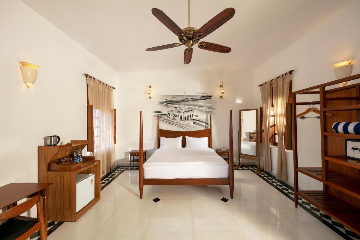 a bedroom with a bed and a ceiling fan at Grand Hotel D'Europe in Puducherry