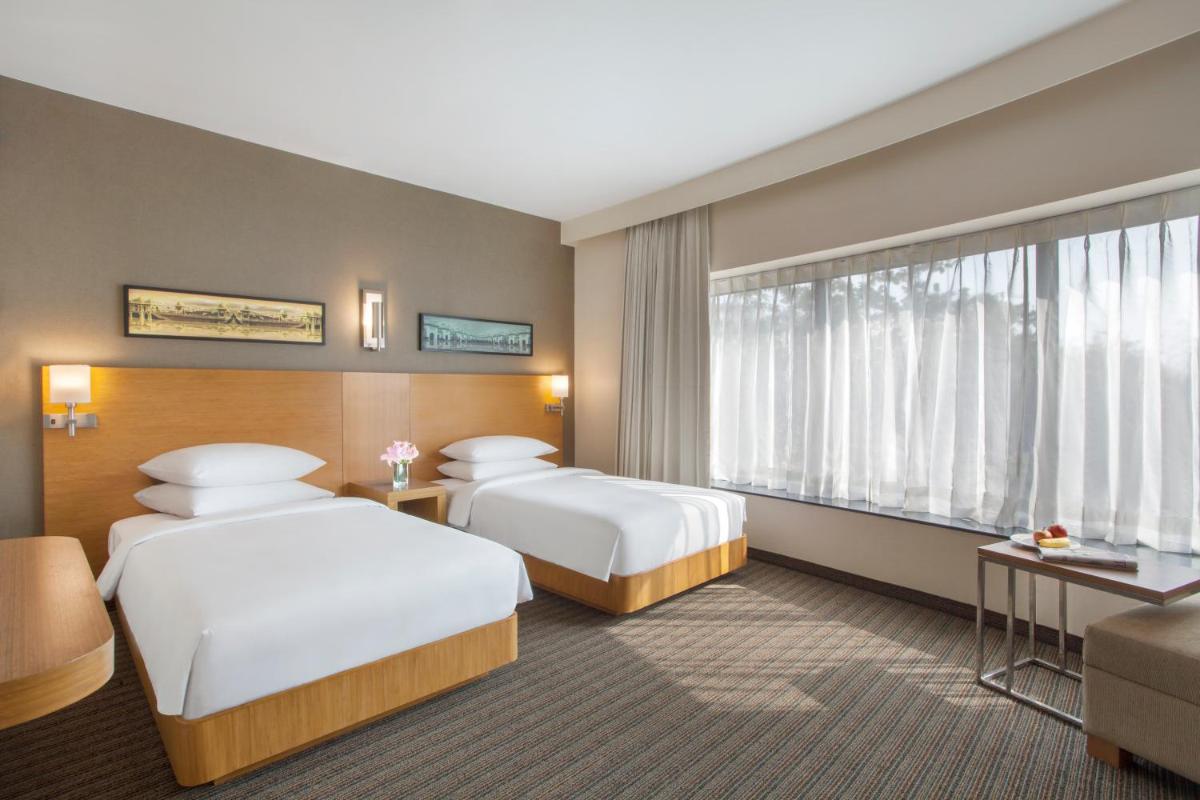 a hotel room with two beds and a couch at Hyatt Place Hyderabad Banjara Hills in Hyderabad