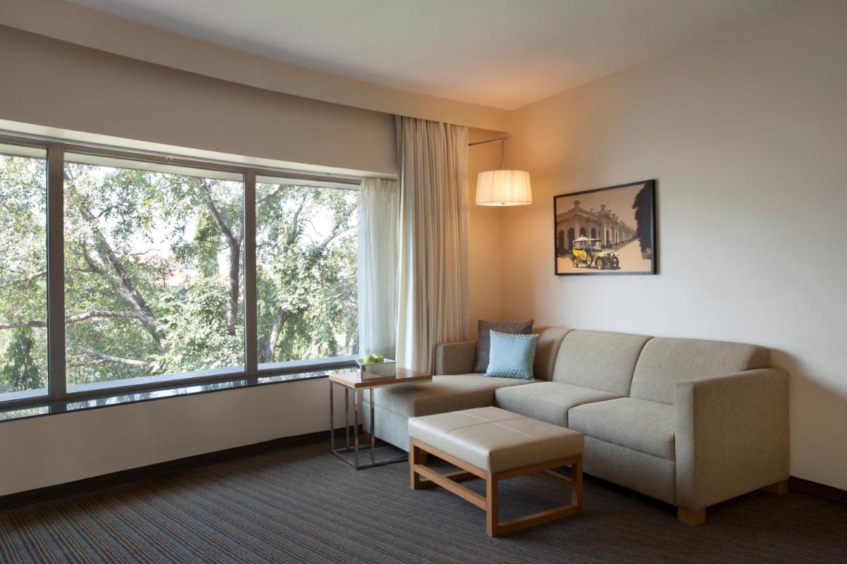 a living room with a couch and a large window at Hyatt Place Hyderabad Banjara Hills in Hyderabad