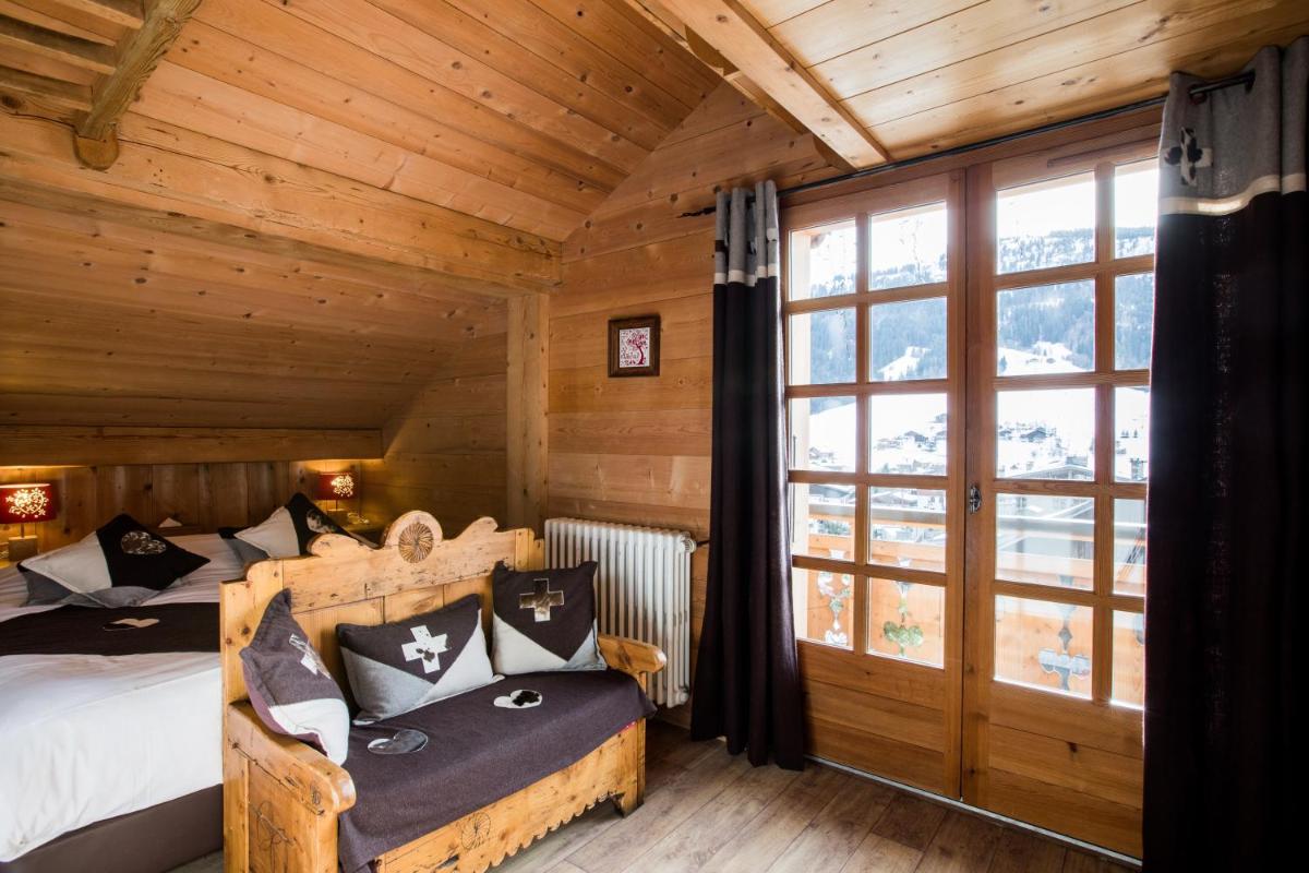 - une chambre dans une cabane en rondins avec un lit et une fenêtre dans l'établissement Les Chalets de La Griyotire, à Praz-sur-Arly
