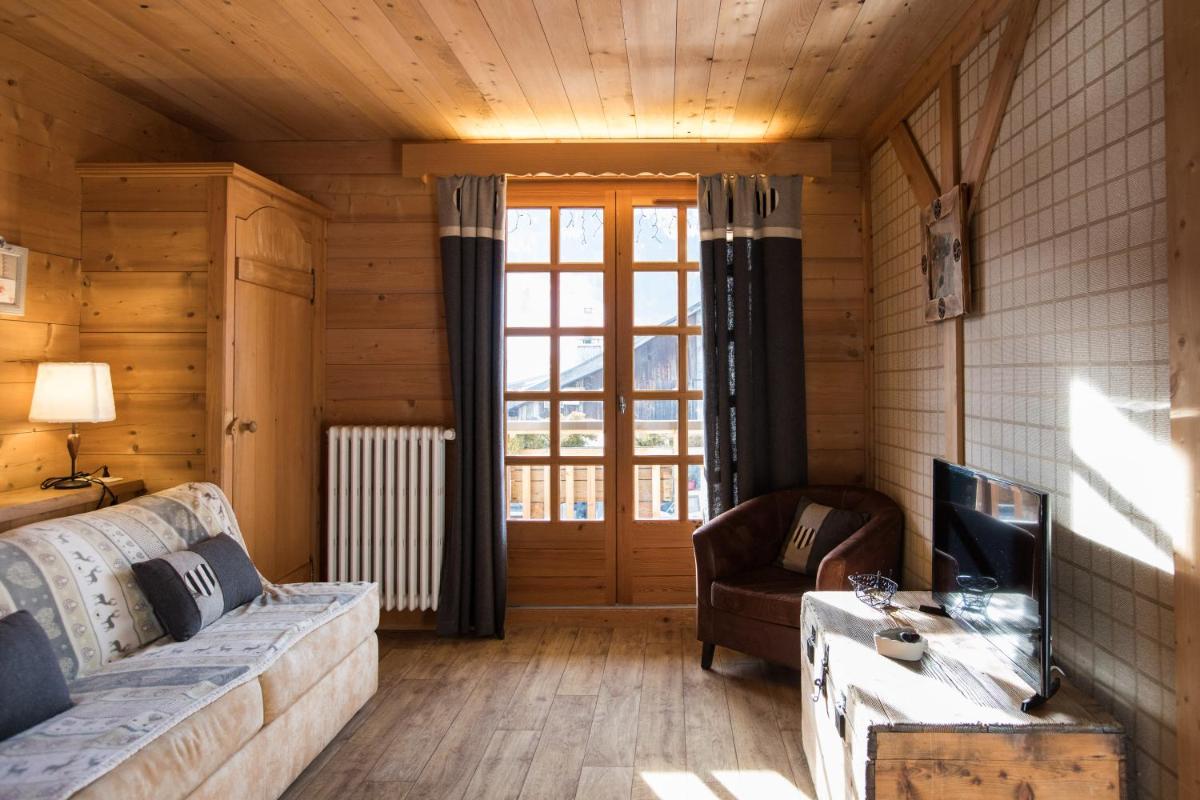 un salon avec un canapé et une télévision dans l'établissement Les Chalets de La Griyotire, à Praz-sur-Arly